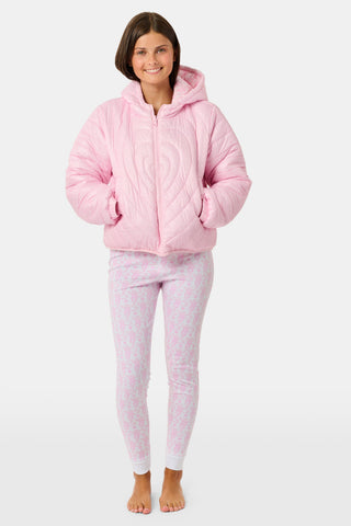 A person wearing a light pink SOPHISTICA Kids Lovely Monkey/Hearts Reversible Puffer Jacket made of durable nylon with repeating heart-shaped quilting and a hood.