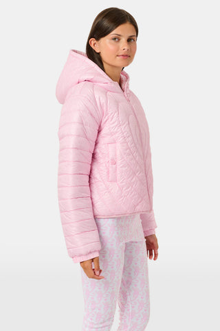 A person wearing a light pink SOPHISTICA Kids Lovely Monkey/Hearts Reversible Puffer Jacket made of durable nylon with repeating heart-shaped quilting and a hood.