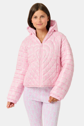 A person wearing a light pink SOPHISTICA Kids Lovely Monkey/Hearts Reversible Puffer Jacket made of durable nylon with repeating heart-shaped quilting and a hood.