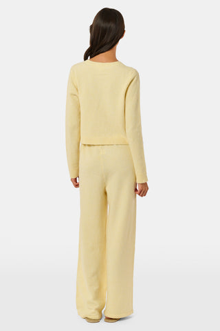 A person wearing the Roller Rabbit Gaia Pant paired with a light yellow knit sweater and beige slippers stands against a plain white background.