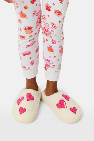 Kids Hearts Fuzzy Slippers: a pair of cream-colored fuzzy kids slippers decorated with red heart appliques.