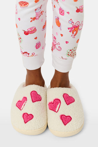 Kids Hearts Fuzzy Slippers: a pair of cream-colored fuzzy kids slippers decorated with red heart appliques.