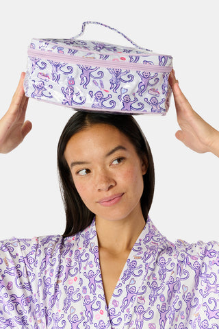 A person dressed in a purple robe adorned with a playful monkey pattern holds the STREET SMART Get Ready With Me Carry All Case—ideal as a makeup organizer or for storing your GRWM essentials—against a plain background.