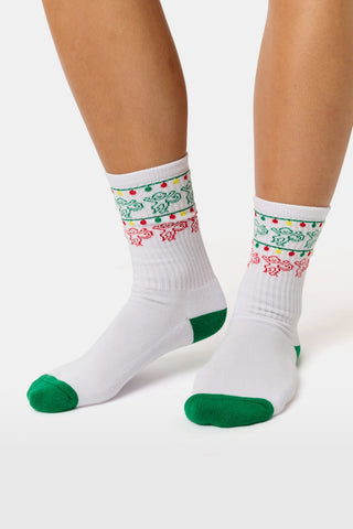 STREETSMART Deck The Halls Crew Socks are white holiday socks with green heels and toes, featuring a pattern of dancing gingerbread men and colorful light strings around the upper cuffs.
