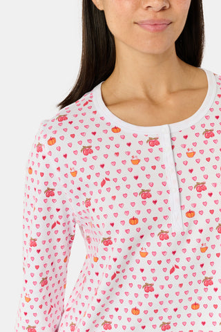A person stands facing forward, barefoot against a plain white background, wearing Roller Rabbit’s Autumn Hearts Pajamas—women’s long-sleeve and long-pant pajamas crafted from soft Pima cotton in a pink and white polka-dot print.