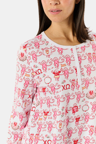 The Roller Rabbit Chi Omega Monkey Pajamas are a long-sleeve Henley top pajama set with matching pants, featuring a white background decorated with red, pink, and gray hearts, XOXO motifs, and playful accents. The pants are designed with a comfortable mid-rise elastic waist.