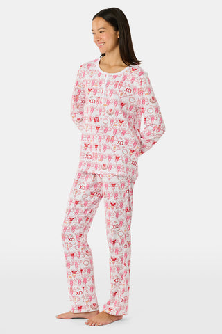 The Roller Rabbit Chi Omega Monkey Pajamas are a long-sleeve Henley top pajama set with matching pants, featuring a white background decorated with red, pink, and gray hearts, XOXO motifs, and playful accents. The pants are designed with a comfortable mid-rise elastic waist.