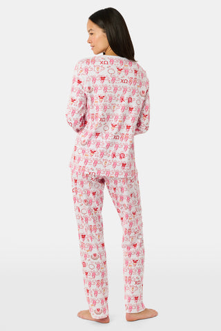 The Roller Rabbit Chi Omega Monkey Pajamas are a long-sleeve Henley top pajama set with matching pants, featuring a white background decorated with red, pink, and gray hearts, XOXO motifs, and playful accents. The pants are designed with a comfortable mid-rise elastic waist.
