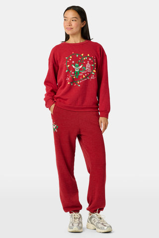 Holly berry red US BLANKS Deck The Halls Bea Sweatpants featuring a small embroidered graphic of a green character wearing a holiday sweater on the right hip.