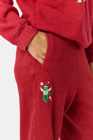 Holly berry red US BLANKS Deck The Halls Bea Sweatpants featuring a small embroidered graphic of a green character wearing a holiday sweater on the right hip.