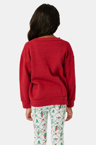 A child wears a Kids Deck The Halls Andie Sweatshirt featuring a heart made of festive lights, a cartoon monkey, and a Christmas tree graphic, paired with patterned leggings showing elves and snowmen.