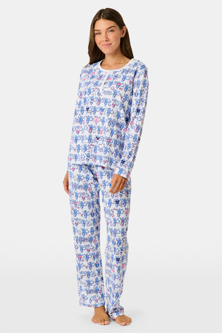 A woman in Roller Rabbit Delta Gamma Monkey Pajamas sits on steps, eating from a cup of ice cream topped with rainbow sprinkles using a white plastic spoon.