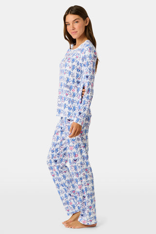 A woman in Roller Rabbit Delta Gamma Monkey Pajamas sits on steps, eating from a cup of ice cream topped with rainbow sprinkles using a white plastic spoon.