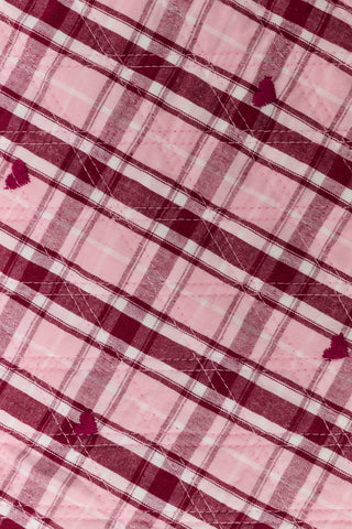 A young girl wearing a pink and white plaid hearts Kids Plaid Hearts Finn Jacket and a matching skirt.