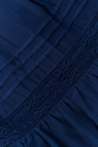 A person wearing a navy tiered silk Fleet Skirt by SOPHISTICA and knee-high suede boots.