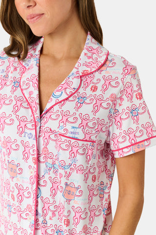 Introducing the Roller Rabbit Gamma Phi Beta Monkey Polo Pajamas: a short-sleeve Pima cotton set featuring a button-up top and matching shorts, adorned with a whimsical pink and blue monkey pattern and red trim on a crisp white background.