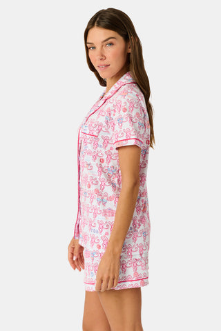 Introducing the Roller Rabbit Gamma Phi Beta Monkey Polo Pajamas: a short-sleeve Pima cotton set featuring a button-up top and matching shorts, adorned with a whimsical pink and blue monkey pattern and red trim on a crisp white background.