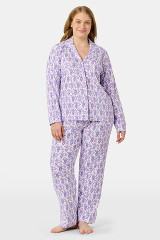 A woman smiles while wearing the TEXPIMA Get Ready With Me Blake Robe, featuring a knee-length cut and a purple and pink paisley pattern, tied at the waist, against a plain white background.