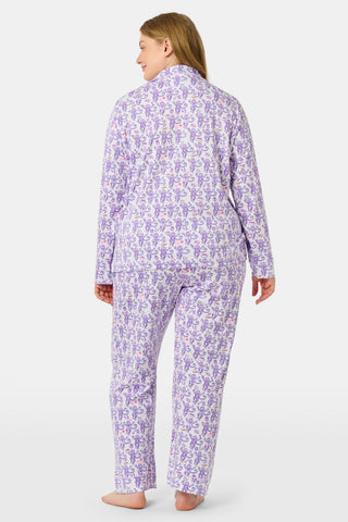 A woman smiles while wearing the TEXPIMA Get Ready With Me Blake Robe, featuring a knee-length cut and a purple and pink paisley pattern, tied at the waist, against a plain white background.
