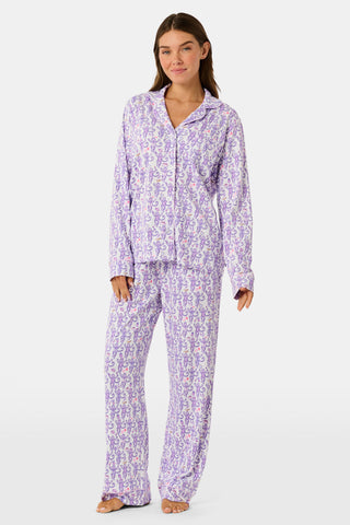 A woman smiles while wearing the TEXPIMA Get Ready With Me Blake Robe, featuring a knee-length cut and a purple and pink paisley pattern, tied at the waist, against a plain white background.