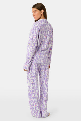 A woman smiles while wearing the TEXPIMA Get Ready With Me Blake Robe, featuring a knee-length cut and a purple and pink paisley pattern, tied at the waist, against a plain white background.
