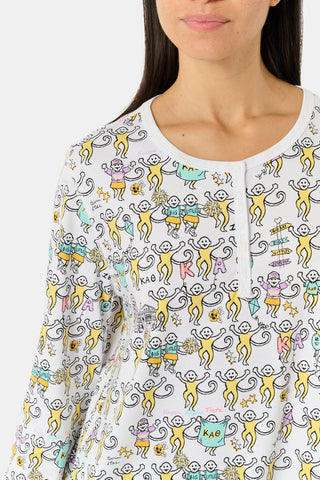 The Roller Rabbit Kappa Alpha Theta Monkey Pajamas set features a white, long-sleeved buttoned top and matching pants, both adorned with a vibrant all-over cartoon print of playful animal characters, including cheerful monkeys.