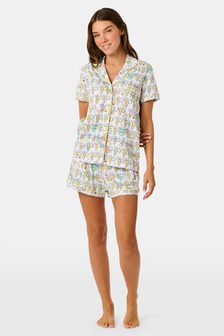 The Kappa Alpha Theta Monkey Polo Pajamas from Roller Rabbit are a short-sleeve button-up set with matching shorts, showcasing a lively print of colorful cartoon monkeys and doodles on a crisp white background. They feature an elastic waistband for comfort and are crafted from soft Pima cotton for a gentle feel.
