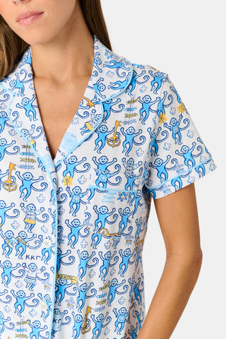 The Roller Rabbit Kappa Kappa Gamma Monkey Polo Pajamas feature a short-sleeve button-up pajama shirt with a front button placket and matching shorts with an elastic waistband, adorned with a playful blue monkey and yellow motif on a white background. Crafted from soft Pima cotton for extra comfort.