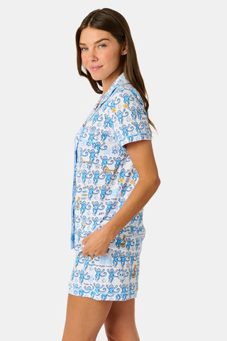 The Roller Rabbit Kappa Kappa Gamma Monkey Polo Pajamas feature a short-sleeve button-up pajama shirt with a front button placket and matching shorts with an elastic waistband, adorned with a playful blue monkey and yellow motif on a white background. Crafted from soft Pima cotton for extra comfort.
