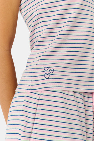 A woman smiles while wearing the Roller Rabbit Striped Lia Set, which features a sleeveless, pink and white striped Pima cotton tank with adjustable straps and matching shorts with ruffled hems and an elastic waistband, standing against a plain light background.