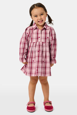 A girl wears a pink and white plaid hearts SAPPHIRE Kids Plaid Hearts Isabelle Dress with long sleeves and light-colored ballet flats.