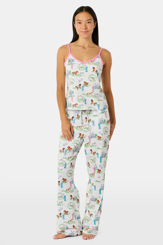 The Saddle Up Joanie Pajamas by Roller Rabbit feature a white sleeveless top and long pants with pink trim. Both pieces are made from soft Pima cotton and decorated with colorful cartoon animal and house prints scattered across the fabric.