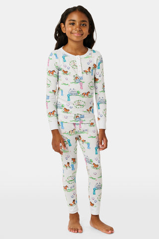 Introducing the Kids Saddle Up Pajamas by Roller Rabbit—a children’s pajama set crafted from premium Pima cotton, featuring a whimsical equestrian print of horses, castles, and greenery on a white background. This high-quality set includes a long-sleeve top and matching pants.
