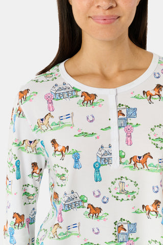 Meet the Saddle Up Pajamas by Roller Rabbit: a long-sleeved Pima cotton set on a white background, adorned with vibrant animal and tree motifs. The top features buttons at the neckline, while the elastic-waist pants offer comfy ease—ideal for horse girls who appreciate playful patterns and cozy comfort.