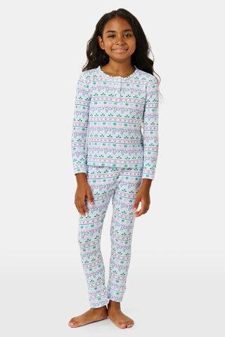 A child wears the SERFLEX Kids Snowday Stripe Iggy Play Set, featuring long sleeves and matching pants with a colorful horizontal stripe pattern of reindeer, snowflakes, and hearts.
