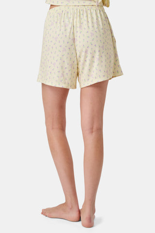The Mini Monkey Blossom Brooklyn Boxer by Roller Rabbit features light yellow Pima cotton with a delicate pastel floral print and an elastic waistband. Displayed on a plain white background, these comfortable women’s loungewear sleep shorts are perfect for relaxing at home.