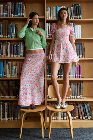 A Roller Rabbit Kids Garden Gate Floral Alexis Skirt with matching briefs, both showcasing a pink, green, and white flower pattern, is displayed on a plain white background. This cotton skirt is ideal for girls who love playful floral prints.
