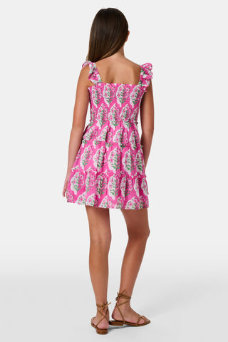 The Kids Ava Floral Ceri Dress by Roller Rabbit is a sleeveless baby dress featuring a smocked bodice and ruffled straps, adorned with green and white leaf patterns on a vibrant pink background, and comes with matching bloomers.