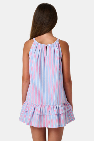 A young girl wearing the Roller Rabbit Kids Sweet Stripe Casey Dress stands in front of lockers, smiling and holding a folder decorated with colorful raindrops.