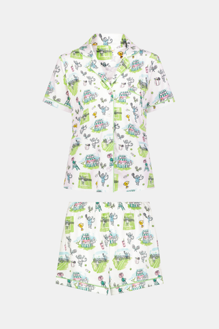 The Roller Rabbit Game, Set, Monkey Polo Pajamas is a two-piece set featuring a short-sleeve button-up shirt and matching shorts. Crafted from soft Pima Cotton, the white fabric is adorned with a playful cartoon animal and house print in green, blue, and yellow tones.