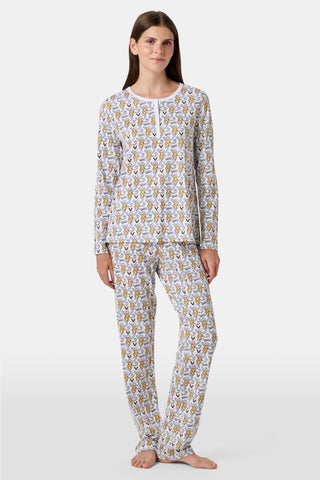 A person stands barefoot wearing the SERFLEX Vanderbilt Lovely Monkey Pajamas, a matching long-sleeve set featuring an allover cartoon animal print. The background is plain and light gray.