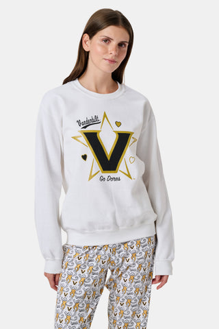 A woman wearing a white FANFAB Vanderbilt Lovely Monkey Crewneck cotton fleece sweatshirt featuring a large V and Go Dores text, paired with white patterned pajama pants, stands against a plain background.