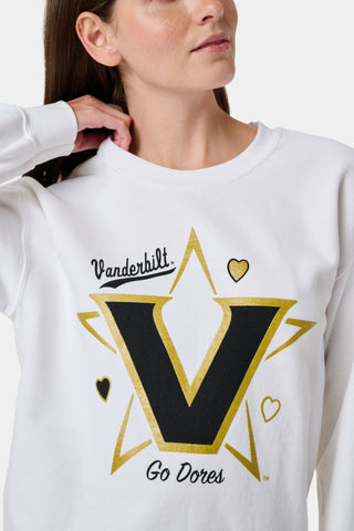 A woman wearing a white FANFAB Vanderbilt Lovely Monkey Crewneck cotton fleece sweatshirt featuring a large V and Go Dores text, paired with white patterned pajama pants, stands against a plain background.