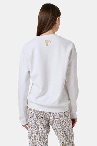 A woman wearing a white FANFAB Vanderbilt Lovely Monkey Crewneck cotton fleece sweatshirt featuring a large V and Go Dores text, paired with white patterned pajama pants, stands against a plain background.