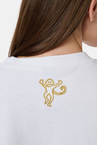 A woman wearing a white FANFAB Vanderbilt Lovely Monkey Crewneck cotton fleece sweatshirt featuring a large V and Go Dores text, paired with white patterned pajama pants, stands against a plain background.