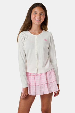 The Roller Rabbit Kids Hearts Pointelle Heidi Cardigan features a white long-sleeve design with playful pink heart details, reminiscent of a classic button-up style, and is displayed against a plain white background.