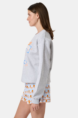 A woman stands facing forward with a neutral expression, wearing the FANFAB Tennessee Crewneck in gray and white shorts featuring an orange and blue pattern, her hand casually tucked into her shorts pocket as she shows off her school pride.