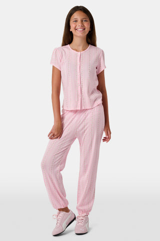The Kids Daisy Heart Stripe Lucy Pants by Roller Rabbit are crafted from soft Pima cotton genie pant fabric in rose pink, featuring an elastic waistband and cuffs, with a subtle striped pattern and small floral designs throughout—making them a charming addition to girls' fashion.