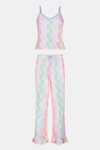 A woman stands barefoot wearing the Roller Rabbit Disco Monkey Lily Set, a matching Pima cotton pajama set featuring a pastel lace-like pattern, sleeveless camisole top, and drawstring pants with pockets.