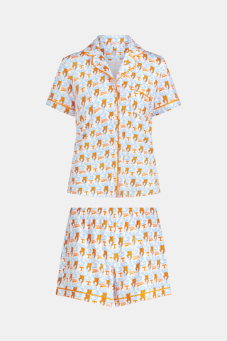 A woman stands barefoot against a plain white background wearing SERFLEX’s Tennessee Lovely Monkey Pajamas: a matching white women’s set with an all-over orange and brown monkey print, featuring long sleeves and full-length pants.